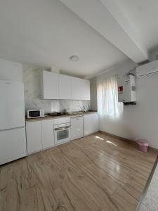 a white kitchen with white cabinets and a wooden floor at Berta Home in Mota del Cuervo