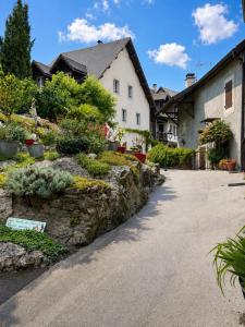 a house with a stone wall in front of a driveway at Le Doux Nid in Chanaz