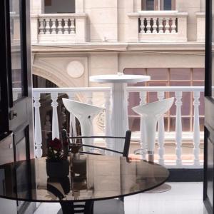 a glass table and chairs in front of a building at Hotel Acropolis Callao in Lima