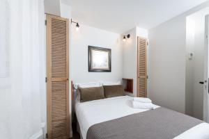 a white bedroom with a bed and a mirror at Les Petits Volets 2 à 100m de la mer in Antibes