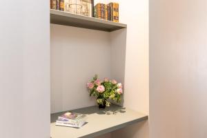 a vase of flowers on a shelf with books at Les Petits Volets 2 à 100m de la mer in Antibes