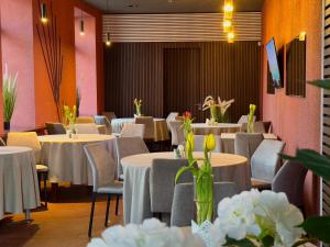 a dining room with tables and chairs and flowers at GRAND Restaurant&Hotel in Daugavpils