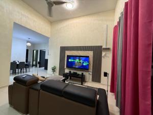 a living room with a couch and a flat screen tv at MiD Guest House in Gambang