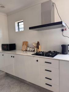 a kitchen with white cabinets and a stove at 3 bedroom house with a mountain view in Mbeya