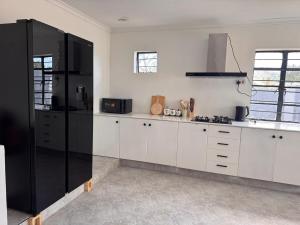 a kitchen with white cabinets and a black refrigerator at 3 bedroom house with a mountain view in Mbeya