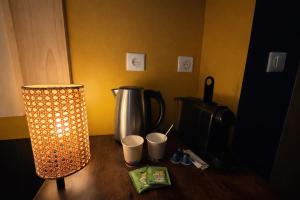 a table with a coffee pot and a lamp on it at Le Doux Nid in Chanaz