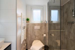 a bathroom with a shower and a toilet and two windows at Ostseecamp Haus Im Eck 142 mit kostenfreier Saunanutzung in Scharbeutz +26 photos