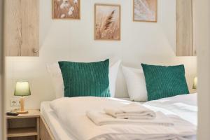 a bed with green and white pillows at Ostseecamp Haus Im Eck 142 mit kostenfreier Saunanutzung in Scharbeutz