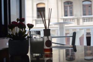 a glass table with a bottle and a vase with flowers at Hotel Acropolis Callao in Lima +8 photos