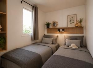 a bedroom with two beds with a teddy bear sitting between them at Camping Cabestan in Bretignolles-sur-Mer