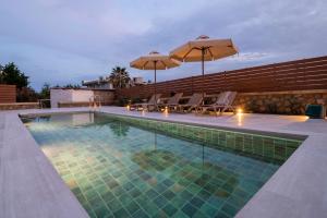 a swimming pool with chairs and umbrellas on a building at Villa Sunrise by the Sea in Kiotari