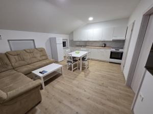 a living room with a couch and a table and a kitchen at Apartma Pri Stevotu in Deskle +13 photos