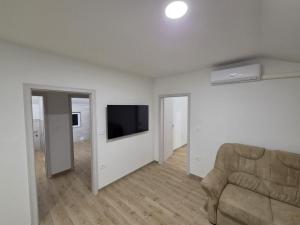 a living room with a couch and a flat screen tv at Apartma Pri Stevotu in Deskle