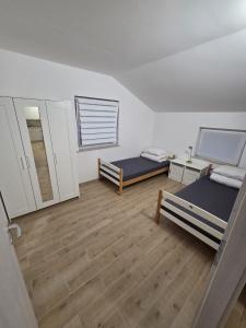 two beds in a room with wooden floors at Apartma Pri Stevotu in Deskle