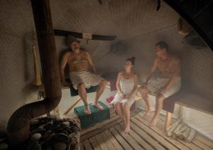 a group of three people sitting on beds in a room at Friends glamping & Sauna in Kutaisi