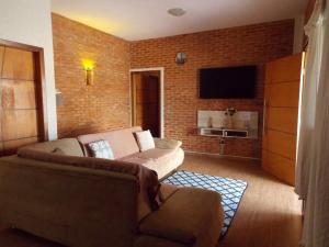ein Wohnzimmer mit einer Couch und einer Backsteinwand in der Unterkunft Cantinho Rústico Brotas SP + Piscina Privativa + Ar Condicionado in Brotas