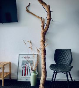 a tree branch in a vase next to a chair at Aparthotel Flughafen Leipzig in Freiroda