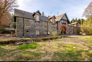 a large stone house with a tree in front of it at The Wood Wing Suite at Bellspool in Peebles
