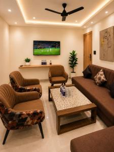 a living room with a couch and chairs and a tv at Velara Hotel & Banquet in Gwalior