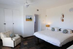 a white bedroom with a bed and a chair at Seaward Studio Suite in Ramsgate