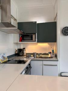 a kitchen with white cabinets and a microwave at St Guenole' Studio Apartment in Landévennec