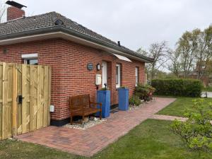 a brick house with a wooden gate and a bench at Haus Juist-Norddeich in Norden