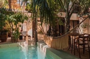 ein Schwimmbecken mit Tisch und Stühlen und Bäumen in der Unterkunft Japoneza Retreat Mérida - Adults Only by Cercana in Mérida