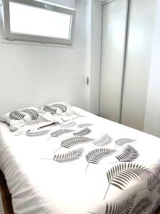 a bedroom with a white bed with a plant printed on it at Duplex cosy 4-6 pers - Terrasse - Grenoble - Vercors in Claix