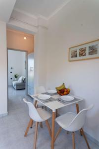a white dining room with a table and chairs at Laloudaki Apartments in Tyros