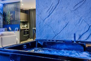 a bathroom with a tub with a blue wall at Le Céleste - Suite romantique immersive climatisée, sauna et spa privatif in Lesparre-Médoc +26 photos