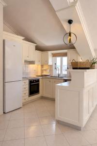 a kitchen with white cabinets and a white refrigerator at Valeria's Apartment in Argostoli
