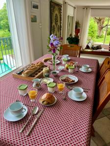 a table with breakfast food on a red table cloth at Montèze Paradis in Saint-Christol-lès-Alès