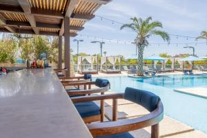 a swimming pool with wooden tables and chairs next to a resort at Palmilla Dunes Luxury Residences in San José del Cabo