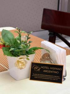 a sign and a vase with a plant on a table at Hispano Argentino in Buenos Aires