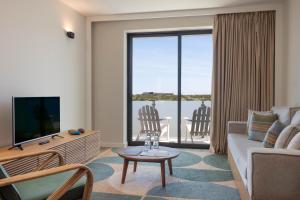a living room with a couch and a tv at Memmo Baleeira - Design Hotels in Sagres