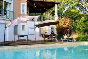 a group of people sitting under an umbrella by a pool at Montèze Paradis in Saint-Christol-lès-Alès