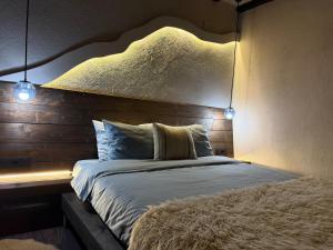 a bedroom with a bed with a headboard and lights at Къща за гости Mia Maria in Tutrakan