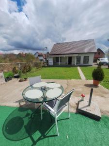a patio with a table and two chairs on the grass at Casa Mara in Ideciu de Jos