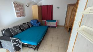 a small room with a blue bed and a red curtain at Independent studio in nature in Saint-Valérien