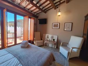a bedroom with a bed and two chairs and a balcony at Cal Blasi in Montblanc