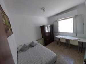 a bedroom with a bed and a desk and a window at Habitación D doble economica in Cantillana