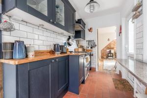 a kitchen with blue cabinets and a red tile floor at Twin Tides in Hythe +22 photos