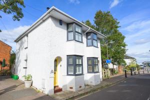 a white house with a yellow door on a street at Twin Tides in Hythe