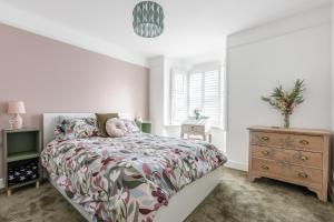 a white bedroom with a bed and a dresser at Twin Tides in Hythe