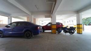 two cars and a motorcycle parked in a parking garage at Peelamedu PSG Tech Near Rooms in Coimbatore