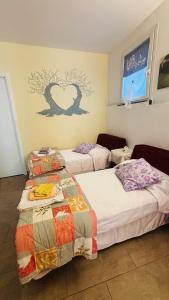 two beds in a room with a heart on the wall at La Casa di Trilli in Moneglia