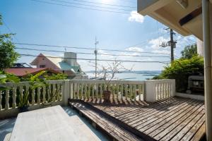 a wooden deck with a bench on a balcony at Green Ocean Kingdom House in Uruma