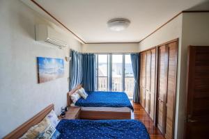 a bedroom with two beds and a large window at Green Ocean Kingdom House in Uruma