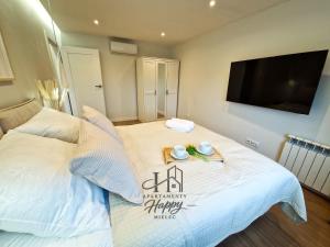 a bedroom with a white bed with a flat screen tv at Happy Deluxe ApartamentyHappy pl in Mielec +14 photos