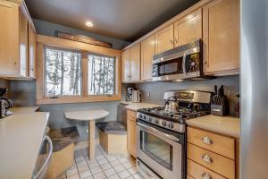 a kitchen with wooden cabinets and a stove top oven at Cabin in the Pines 4 by SummitCove Lodging in Colorado in Keystone